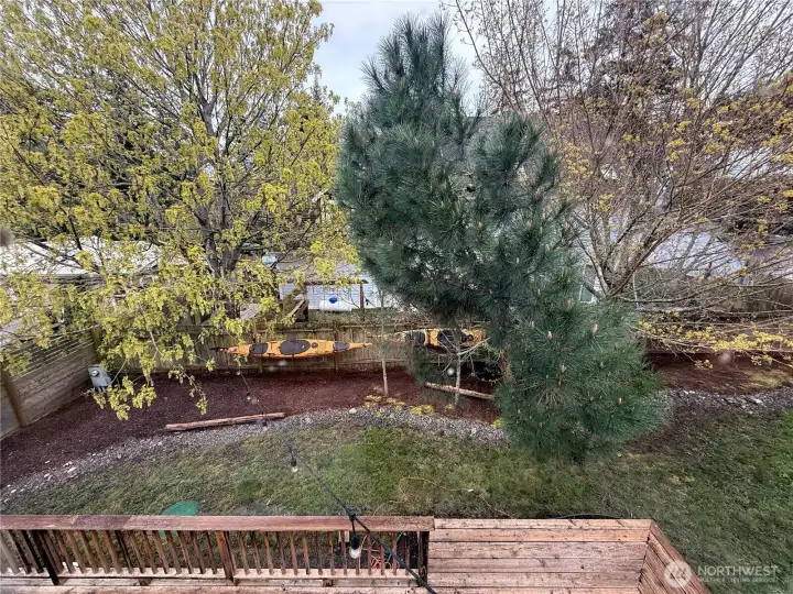 Looking out the primary bedroom window and down over the main level back deck and into the backyard.