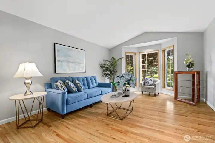 Formal living room with vaulted ceilings and gorgeous hardwood floors and bay window.