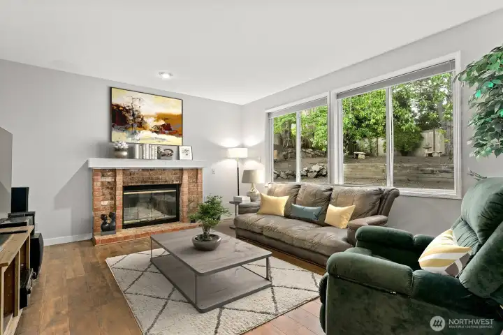 Generous family room with brick fireplace, hearth and a wall of windows with views of the back yard