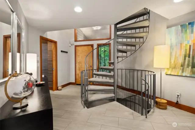 Foyer. Custom spiral staircase leads to Den/ office/ loft above and 1 of 2 ways down to 3 bedrooms, family room and full bath on the lower level.