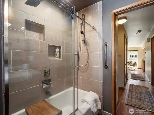 Remodeled shower with tile surround, and original tub.
