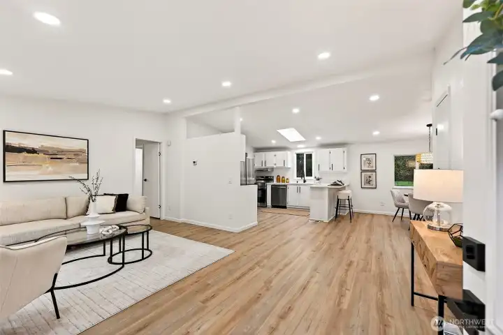 Bright, open-concept living space flows seamlessly into the kitchen, featuring luxury vinyl plank flooring, recessed lighting, a skylight, and a dedicated dining nook.