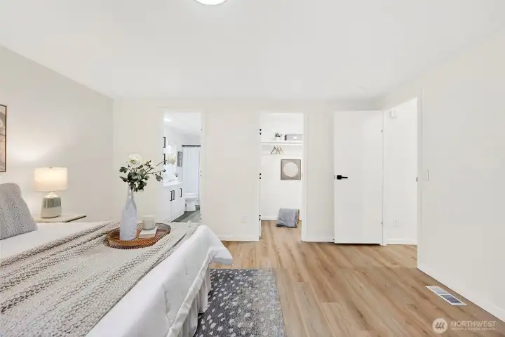 View from the primary bedroom showcasing dual doorways leading to the en suite bath and walk-in closet, with LVP flooring throughout.