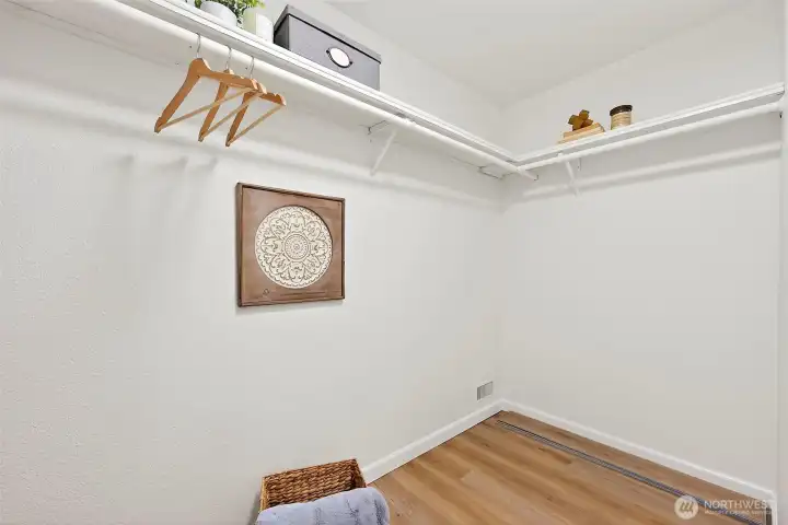 A spacious walk-in closet with full-length hanging rods and upper shelving, offering generous storage off the primary suite.