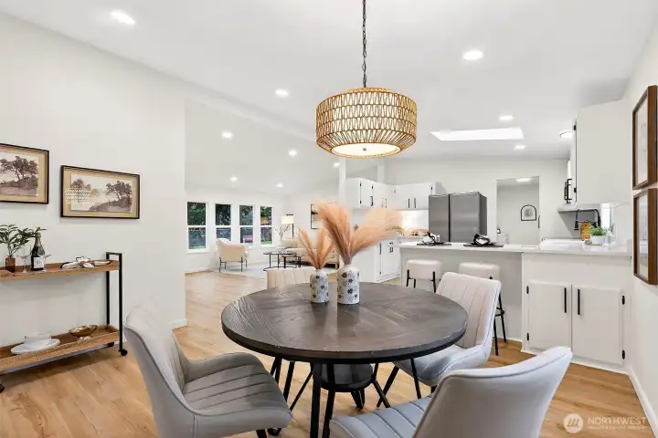 Dining area showcases the rattan pendant, open sightlines to the kitchen and main living room, with recessed lighting and LVP flooring throughout.