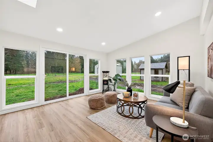 Sun-drenched bonus space with sliding glass door access to the backyard, multiple windows with green views, recessed lighting, and LVP flooring.
