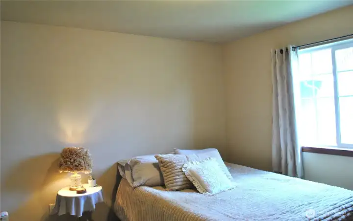 Bright and inviting bedroom with large window, neutral décor, and ample space for furnishings.