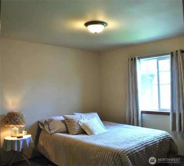 Spacious bedroom showcasing natural light, cozy ambiance, and versatile furniture placement options.