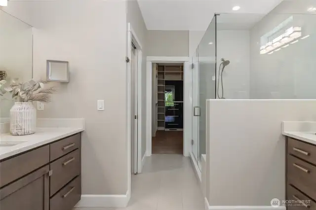 The ensuite bath features separate vanities, a walk-in shower with bench seating, and a private enclosed toilet.