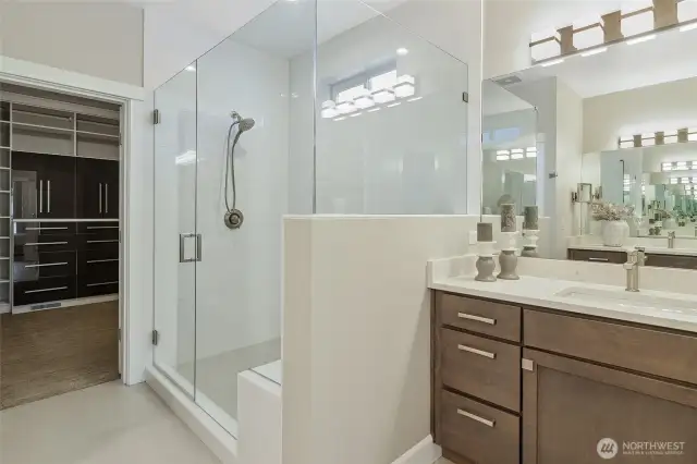 The ensuite bath features separate vanities, a walk-in shower with bench seating, and a private enclosed toilet.