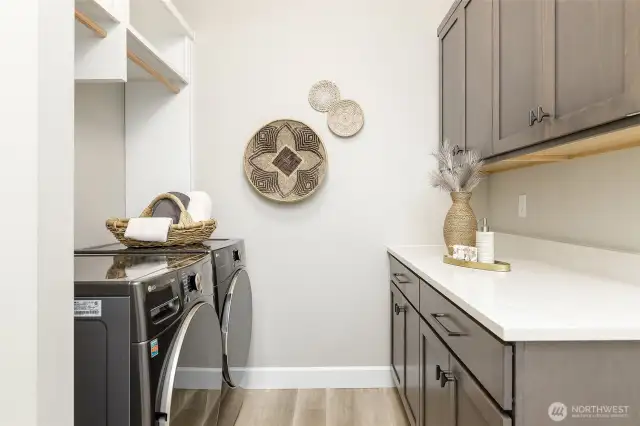 The dedicated laundry room offers exceptional functionality with ample counter space, abundant cabinetry, and convenient hanging racks. Situated just off the garage entrance, it also includes the high-quality LG washer and dryer.