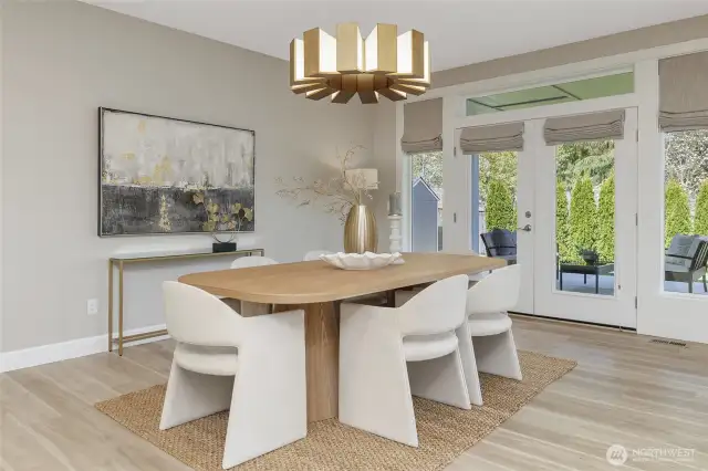 French doors with custom window treatments frame picturesque views of the covered patio and the meticulously landscaped backyard, inviting the outdoors in.