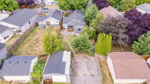 Aerial view showcases the full scope of the property, highlighting the spacious yard, mature landscaping, and detached garage.