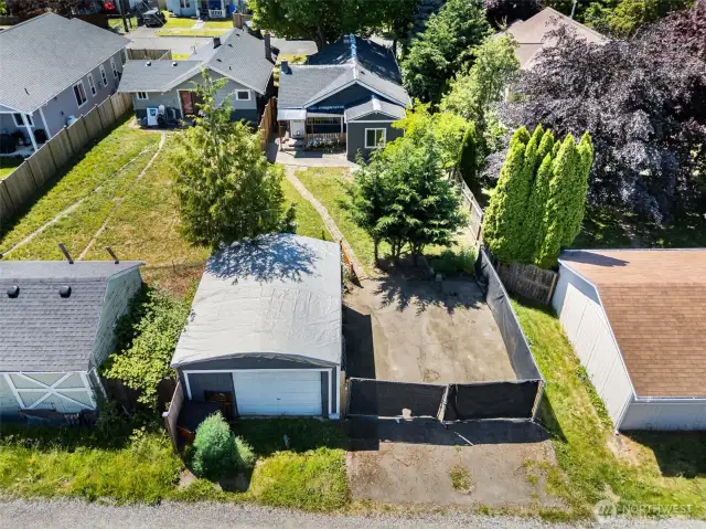 Aerial view showcases the full scope of the property, highlighting the spacious yard, mature landscaping, and detached garage.
