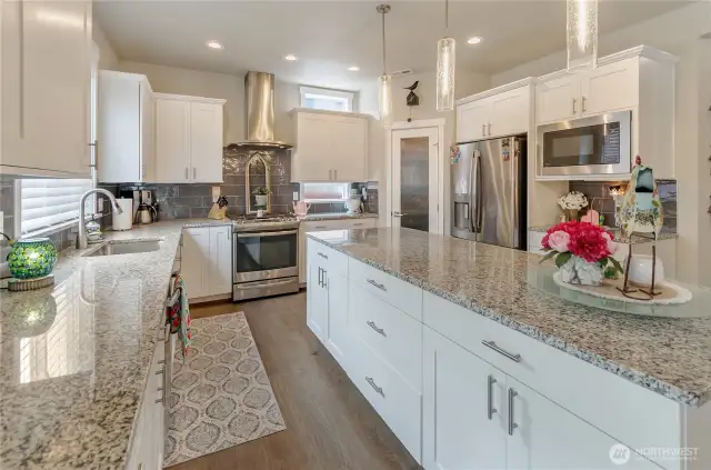 Granite counters and large island are complimented with contrasting full-height subway tile backsplash.