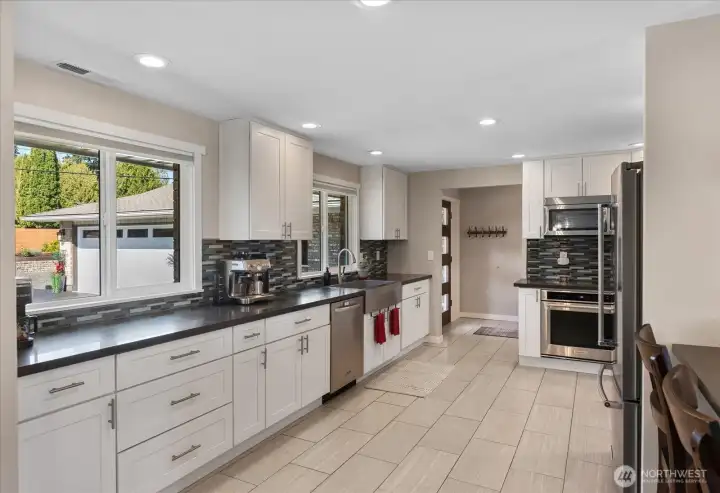 Fully remodeled kitchen, designed with quartz counters, soft-close white shaker cabinets, an apron-front stainless sink, and high-end KitchenAid appliances.