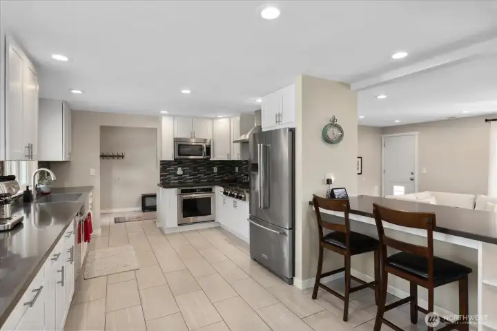 Fully remodeled kitchen, designed with quartz counters, soft-close white shaker cabinets, an apron-front stainless sink, and high-end KitchenAid appliances.  Breakfast bar overlooking the living room.