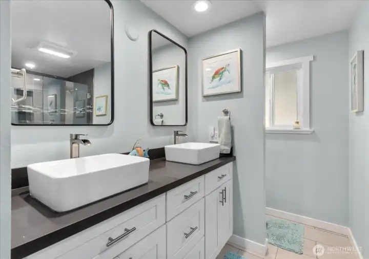 Main bath with a frameless glass shower, quartz counters, double sinks, and new mirrors.