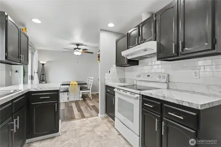 View from your kitchen to your dining room, plenty of cupboards and counter space, included appliances and full-tile backsplash!