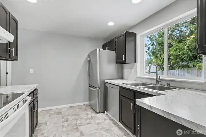 View of your kitchen from the dining room, love the large window over the sink and even more recessed lighting! This is not your typical boring nor claustrophobic alley kitchen, to your left there is an entry to your hallway.
