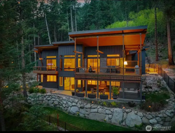 Tucked between the Wenatchee National Forest and the rushing Wenatchee River, this newer construction masterpiece spans over 5 private acres, offering the scale and seclusion of a true luxury retreat. Designed for the elite outdoor enthusiast, this mountain modern estate is the ultimate escape from the city, blending high-end sophistication with world-class high-end tech features. Experience a seamless luxury lifestyle powered by a fully integrated Smart Home system, featuring automated climate and lighting control. With a dedicated, high-speed remote work setup, stay connected while surrounded by soaring ceilings and panoramic forest views. Every corner of this home reflects an absolute attention to every detail, from the artisan finishes to the precision engineering, ensuring a living experience of unparalleled quality. The gourmet kitchen opens to a massive, cedar-lined deck—your private resort for hosting around the built-in BBQ. Afterward, soak in the huge Bullfrog Spa.