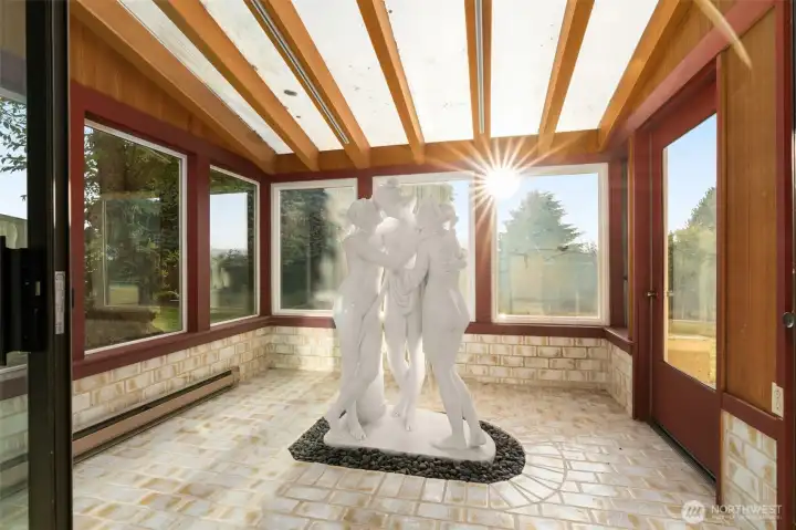 A sunlit solarium showcases a stunning full-size marble statue of the Three Graces, radiating elegance and charm. A sunlit solarium showcases a stunning full-size marble statue of the Three Graces, radiating elegance and charm.
