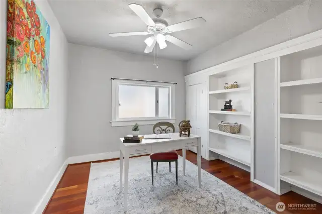 Main floor bedroom with hardwood floor and built-in shelving.