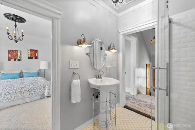 Updated 3/4 bath with tile floor; showing doors to primary bedroom and hallway.  A "continental" bathroom, with 2 entrances.
