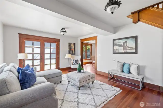 Living room with hardwood flooring, period lighting, and double doors opening out to the south-facing patio.