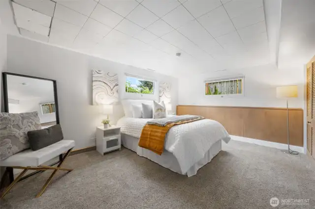 This spacious lower-level Bedroom Three,  includes two horizontal windows that let in natural light while maintaining privacy. Wood panel accents create a warm and restful retreat.