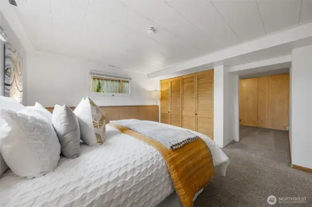 The room features a generous wall-to-wall closet and direct access to an adjacent bonus space. Neutral finishes and a functional layout make it ideal for long-term guests or extended living.