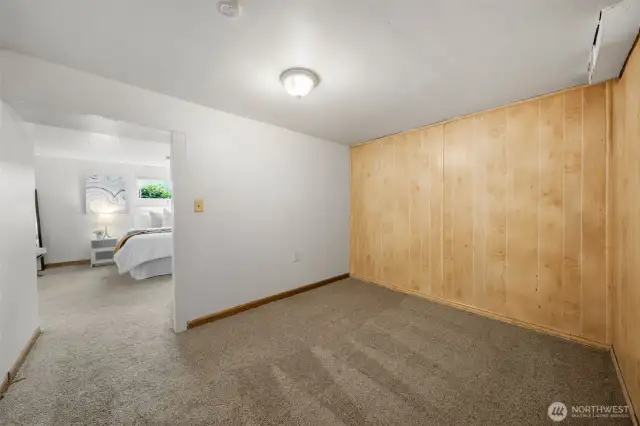 This bonus area just off the lower-level bedroom offers added flexibility for a sitting room, dressing area, or additional storage. Wood paneling and soft carpet make it a natural extension of the adjacent living space.
