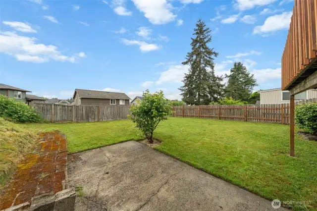 The fenced backyard offers a spacious lawn with plenty of room for play, pets, or gardening. A lower patio area provides a second outdoor space beneath the deck for relaxing or entertaining.