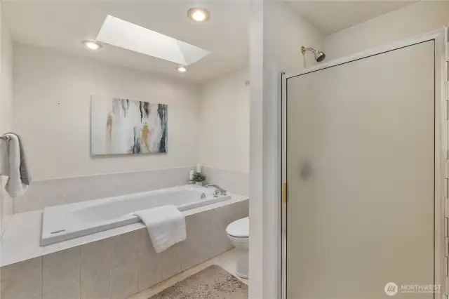 A deep soaking tub, walk-in shower, recessed lighting and a skylight create a comfortable atmosphere in the primary bath.