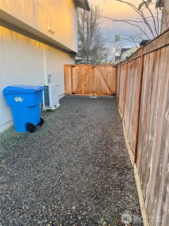 Side yard access with gated fence opening, space suitable for boat or utility trailer, and newer heat pump.
