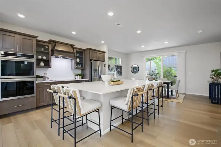 Gather round a large quartz island that anchors the kitchen. Dining room beyond. Gather round a large quartz island that anchors the kitchen. Dining room beyond.