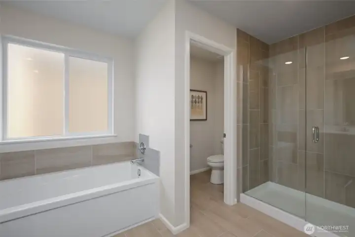 Spa-like primary bath with water closet, soaking tub and glass shower surround. Spa-like primary bath with water closet, soaking tub and glass shower surround.