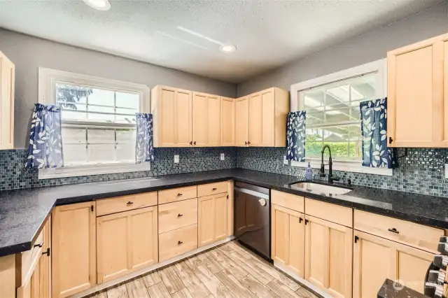 The updated kitchen has beautiful cabinets, quartz countertops, a dramatic backsplash, and lovely tile floors!