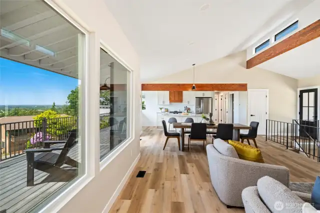 Enjoy effortless indoor-outdoor living with this wide-angle view of the living, dining, and kitchen areas flowing out to the expansive deck and panoramic scenery beyond.