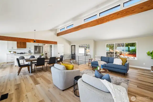 Vaulted ceilings, warm wood beams, and abundant natural light define the open-concept main living area—seamlessly connecting kitchen, dining, and lounging spaces.