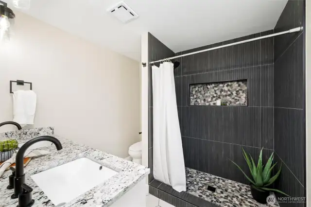 Beautifully updated ensuite bath featuring dual sinks, elegant tilework, and standing shower.