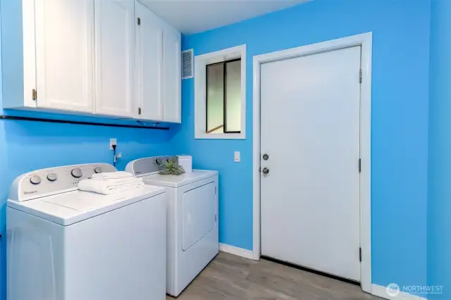 Laundry room with overhead cabinetry and storage. Exit to back door.