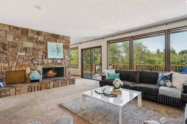 The stone fireplace isn’t just a design feature, it’s a flex. Real stone, real fire, and a serious hearth that begs for a winter movie night (or a bold adult beverage moment). The built-in wood box keeps it practical, but the wall of west-facing windows? Pure wow. Look out over protected trees, part of 110 acres of conservation land next door, and feel like you’re living inside a nature documentary, but with Wi-Fi. Open the slider and step out to your wraparound deck, because that view doesn’t belong behind glass.