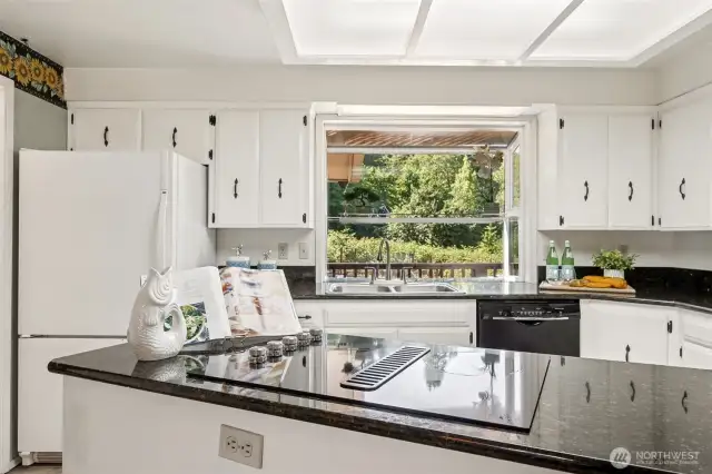 A kitchen with good structure and even better potential. The island has a built-in glass cooktop with a down-draft vent, and the garden window above the sink keeps the space bright and connected to the outdoors