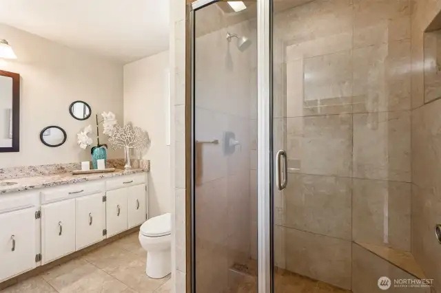 This primary bath is equal parts function and finish. The glass and tile shower has a timeless look and low-maintenance appeal, while the long vanity offers real counter space and clean undermount sink lines.
