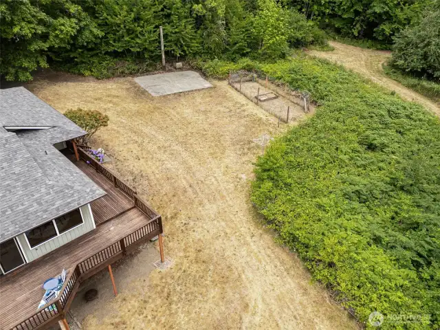 This close-up view shows just how much potential sits right outside the front of the home. The fenced garden is ready for planting, and the concrete pad offers serious versatility. Whether it’s RV parking, a future guest cottage, a backyard office, or a full-on pickleball or basketball court, this space is a blank slate with all the hard work already done.