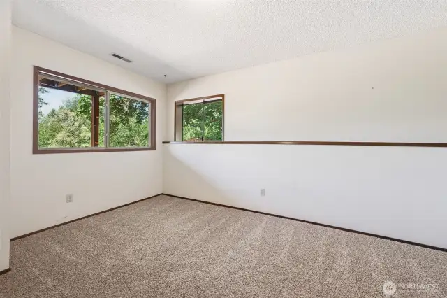 This daylight bedroom gets it right with two windows that look out to peaceful greenery, oatmeal-toned carpet for comfort, and a crisp white backdrop that keeps it bright. The ceiling register connects to the forced air heating system, and the home’s heat pump brings energy-efficient cooling. Simple, functional, and tucked into its own quiet corner of the house.