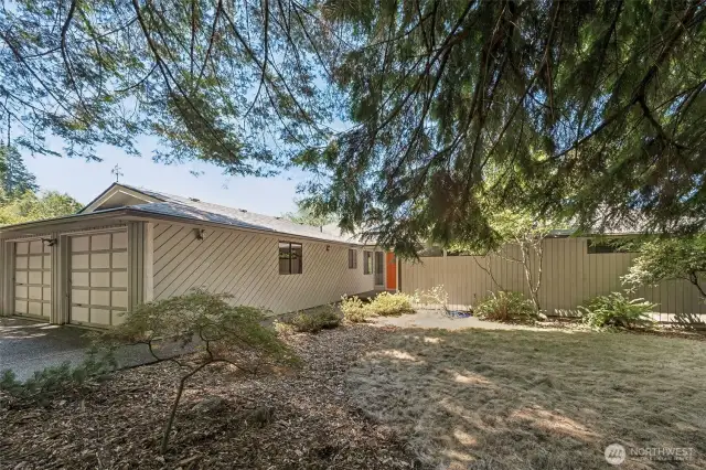 This shot shows off the home’s signature Northwest siding with its diagonal pattern running cleanly along the garage and entry. The two-car garage is fully attached and integrated into the overall design. A mature Japanese maple anchors the front yard with structure and color, while landscape beds and a neat lawn give the exterior a polished, low-fuss finish.