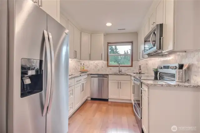 Remodeled kitchen features granite counters, tile backsplash, SS appliances.