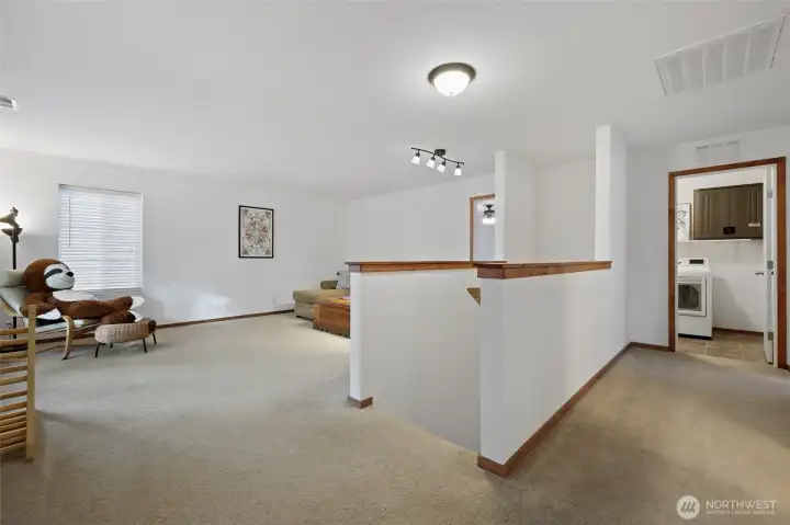 At the top of the stairs is another generous living space, leading to the bedrooms, bathroom, and laundry. Notice the brand new trim throughout, adding a warm wood tone to the fresh white walls.